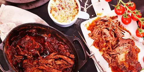 Saftigt pulled beef i en gjutjärnsgryta, serverat med krispig coleslaw och färska tomater. Perfekt för en mysig middag.