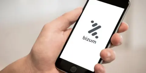Mano sujetando un smartphone con la app Bizum abierta. Aprende como devolver un bizum fácilmente.