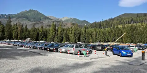 Parking pełen aut pod Tatrami, gotowych na wycieczkę nad Morskie Oko.