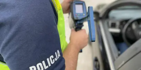 Policjant mierzy prędkość samochodu radarem.