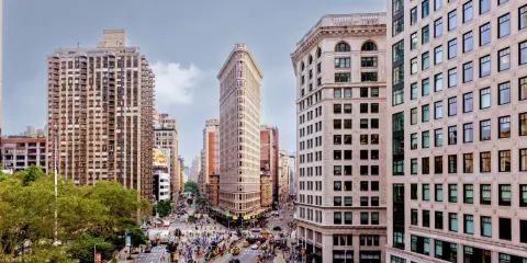 Vista aérea de Nueva York con el icónico edificio Flatiron en el centro. Los planos de la ciudad muestran la intersección de calles y la arquitectura circundante.