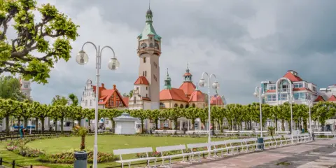 Malowniczy widok na deptak w Sopocie, z charakterystyczną wieżą i budynkami w stylu secesyjnym. Idealne miejsce na spacer między Gdańskiem a Gdynią.