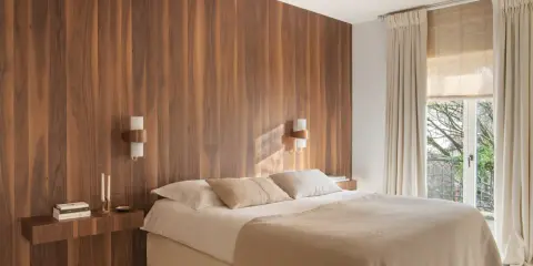 Dormitorio con cabecero de madera natural, creando un ambiente sereno y un cabecero feng shui. Cama confortable con mantas cálidas y luz tenue.