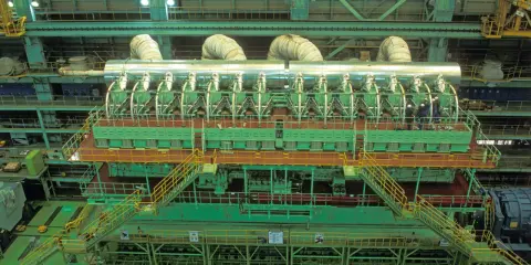Vue aérienne d'un moteur de bateau massif, le plus gros moteur de bateau jamais construit, avec des ouvriers inspectant son imposante structure verte et argentée.
