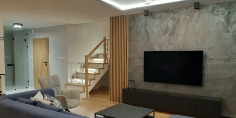 Nowoczesny salon z szarą ścianą, telewizorem i drewnianymi lamelami. Zobacz, z czym łączyć lamele, by stworzyć przytulne wnętrze.