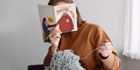 Dziewczyna czyta książkę o swetrach, jedząc spaghetti z włóczki. Jak znaleźć początek włóczki?