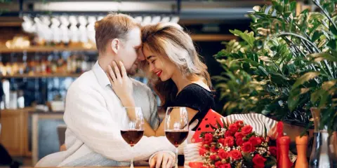 Para świętuje 13 rocznicę ślubu w restauracji, z kieliszkami wina i bukietem czerwonych róż.