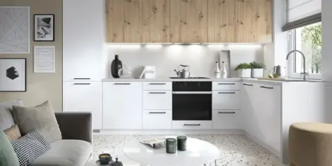 Nowoczesna mała kuchnia z salonem 20m2. Białe meble, drewniane fronty szafek, szara kanapa i stoliki kawowe.