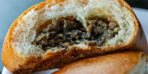 Puszysta bułka z pieczarkami, przekrojona na pół, odsłaniająca aromatyczne, drobno posiekane grzyby.