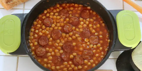 Un plato humeante de garbanzos con chorizo, listo para disfrutar con pan crujiente.