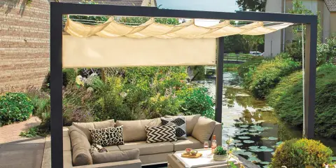 Nowoczesna pergola z wysuwanym daszkiem to świetny sposób, jak osłonić taras od wiatru i słońca. Wygodny narożnik i stolik zachęcają do relaksu.