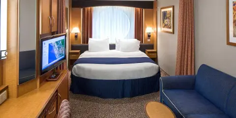 Cabina garantita MSC quando viene assegnata: letto matrimoniale, divano blu, TV e oblò rotondo.