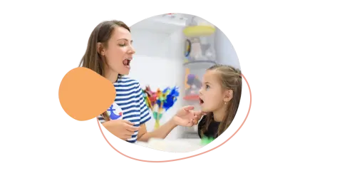 Logopädin zeigt einem Mädchen, wie man Laute richtig formt. So lernen Kinder am besten neue Sprechfähigkeiten.