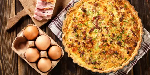 Quiche Lorraine, un classique de la gastronomie lorraine, avec ses ingrédients frais : œufs, lardons et herbes.