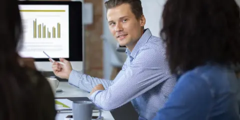 Un consultant en communication digitale explique des graphiques à ses collègues lors d'une réunion.