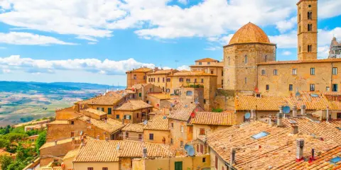Panoramica di Volterra, con le sue case in pietra e tetti in cotto, che si estende verso le colline toscane, ricordando la bellezza di San Gimignano.