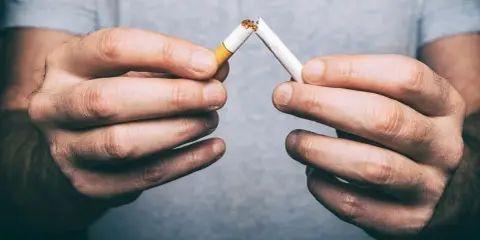 Hände brechen Zigarette. Schluss mit dem Rauchen, besonders bei Magen-Darm-Problemen.