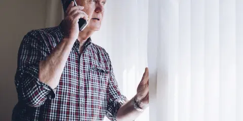 Zaniepokojony starszy mężczyzna rozmawia przez telefon, szukając informacji, gdzie zgłosić zaniedbywanie osoby starszej.