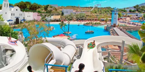 ¡Diversión en el parque acuático Cantabria! Niños disfrutan toboganes y piscina de olas bajo el sol.