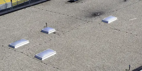 Flachdach mit Kiesbelag und mehreren Lichtkuppeln. Die harte Bedachung bietet Brandschutz und schützt vor Witterungseinflüssen.