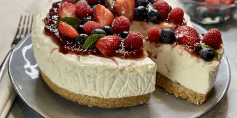 Deliziosa torta fredda allo yogurt, guarnita con fragole, lamponi, mirtilli e menta. Perfetta per un dessert rinfrescante.