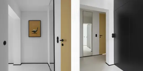 Minimalistyczny, mały przedpokój inspiracje ściany: złote i czarne drzwi, lustro, grafika z fotelem Eamesa.