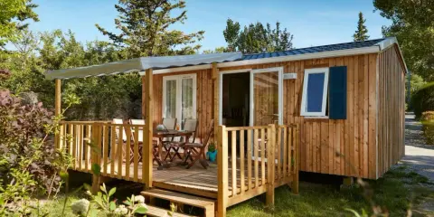 Mobil-home en bois avec terrasse, table et chaises. Découvrez quelle condition pour mettre un mobil-home sur son terrain.