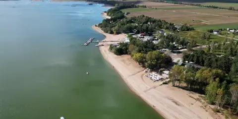 Piękny widok na Mietków Zalew z piaszczystą plażą, mariną i zielonymi terenami. Idealne miejsce na wypoczynek.