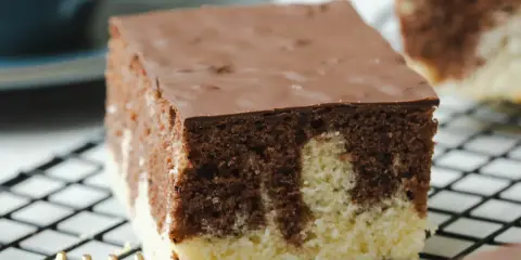 Ein Stück saftiger Marmorkuchen vom Blech, mit Schokoladenglasur, auf einem Kuchengitter.