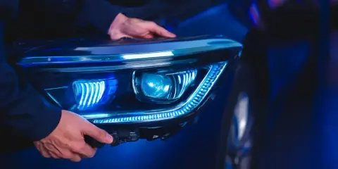 Man installing a modern LED headlight assembly, upgrading from halogen.