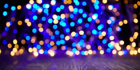 Luci blu e dorate creano un magico effetto bokeh su uno sfondo scuro, con un piano in legno in primo piano.
