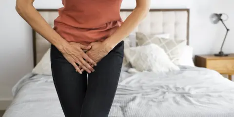 Mujer con las manos en el abdomen, sintiendo dolor de ovarios antes de la regla.