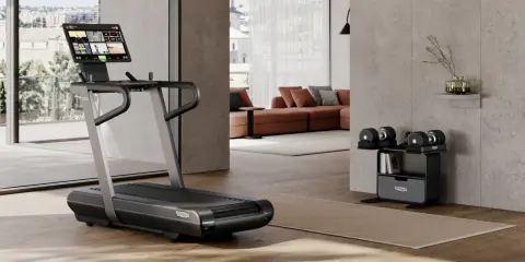 Un tapis de course et des haltères ajustables pour faire une salle de sport chez soi. Un espace moderne et fonctionnel pour le fitness à domicile.