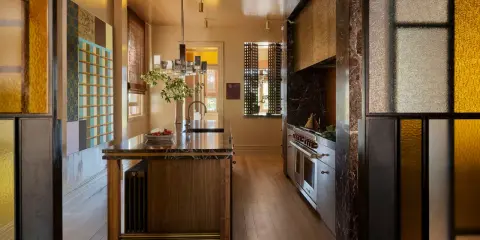 Cocina de lujo con isla de mármol, electrodomésticos de acero inoxidable y detalles en vidrio de colores. Una clara tendencia en cocinas modernas y sofisticadas.
