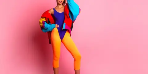 Kobieta w neonowym stroju kąpielowym, pomarańczowych legginsach i kolorowej kurtce, stylizacja inspirowana modą damską lat 90.