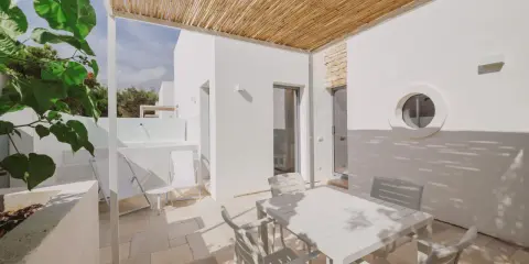 Terrazza con tavolo e sedie bianche, tettoia in bambù, tipica del Nicolaus Club Meditur Village.