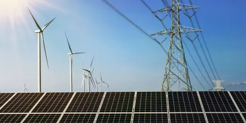 Solarpanels und Windräder, Teil von regenerativen Kraftwerken, unter blauem Himmel mit Strommasten.