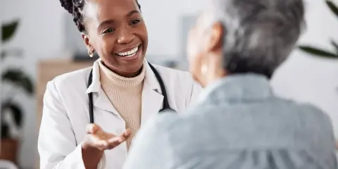 Doctora sonriente explica a paciente sobre síntomas de clamidia en mujeres, ofreciendo apoyo y claridad.
