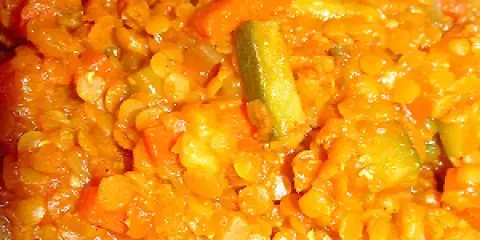 Un plat coloré de lentilles corail avec des morceaux de carottes et de courgettes. Une recette végétarienne savoureuse et réconfortante.