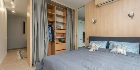 Chambre moderne avec lit douillet, dressing ouvert et rideaux gris. Le prix pour peindre une chambre de 12m2 dépend des finitions.