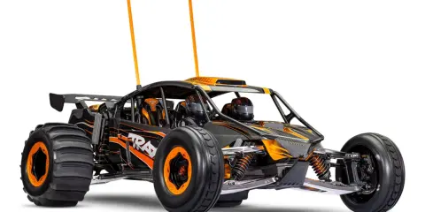 Schwarzes und orangefarbenes offroad elektroauto mit großen Reifen und zwei Antennen, bereit für jedes Abenteuer.