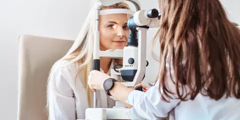 Kobieta z blond włosami u optometrysty, badanie wzroku. Czyżby to było zamglone widzenie po przebudzeniu?
