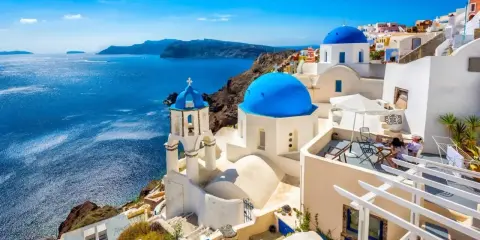 Santorini, Grecja. Białe domy z niebieskimi kopułami nad morzem. Idealne miejsce, gdzie do Grecji na wakacje.
