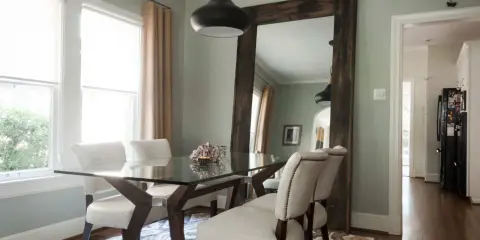 Un grand miroir rustique reflète la salle à manger, offrant une idée de où mettre un miroir dans une salle à manger pour agrandir l'espace.