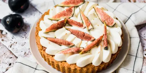 Tarte aux figues fraîches et crème fouettée, décorée de feuilles d'or.