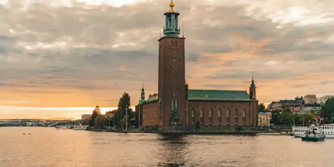Stadshuset i Stockholm vid solnedgången. En vacker vy som inspirerar till roliga saker att göra i Stockholm, som en båttur eller promenad längs vattnet.
