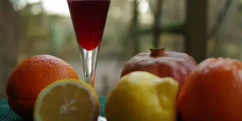 Szklanka z czerwonym napojem, obok pomarańcze, cytryna i granat. Czy to grenadyna? Hajduczek naturalnie.