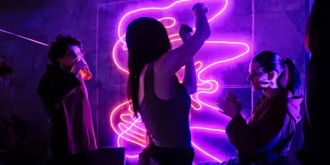Ludzie bawią się przy modnych piosenkach w klubie z neonowym oświetleniem.