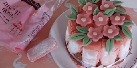 Charlotte aux biscuits roses de Reims, décorée de fleurs en pâte d'amande. Un biscuit rose saupoudré de sucre est à côté.