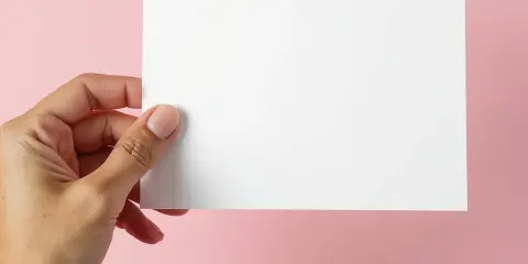Dłoń trzyma białą kartkę, idealną na zaproszenie na imprezę firmową.